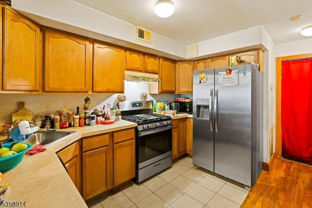 kitchen with stainless steel appliances, under cabinet range hood, light countertops, and brown cabinetry