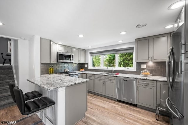 110 William St, Clark Twp, NJ 07066 - kitchen with stainless steel appliances, gray cabinets, a peninsula, a sink, and decorative backsplash