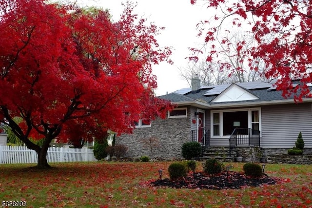 110 William St, Clark Twp, NJ 07066 - view of front facade with stone siding, solar panels, and a chimney