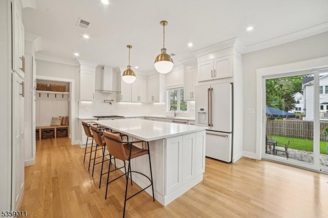 84 Elmwood Ave, Chatham Boro, NJ 07928 - kitchen with white fridge with ice dispenser, wall chimney range hood, decorative backsplash, light countertops, and a breakfast bar area