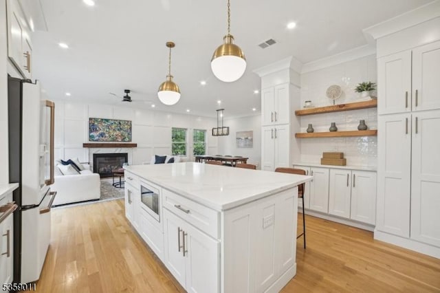 84 Elmwood Ave, Chatham Boro, NJ 07928 - kitchen featuring white refrigerator with ice dispenser, light wood-style floors, open floor plan, a glass covered fireplace, and white cabinets