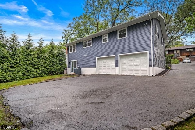 192 Mohawk Trl, Wayne Twp, NJ 07470 - view of property exterior featuring a garage, asphalt driveway, and central air condition unit