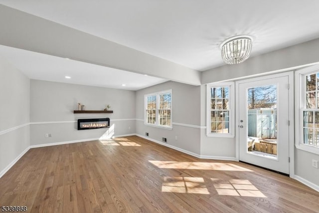 231 Sutphin Ln, Hillsborough Twp, NJ 08844 - unfurnished living room featuring a chandelier, wood finished floors, a glass covered fireplace, baseboards, and recessed lighting