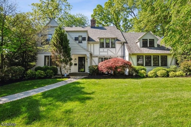 42 Haddonfield Rd, Millburn Twp, NJ 07078 - tudor-style house with a front lawn, a chimney, roof with shingles, and stucco siding