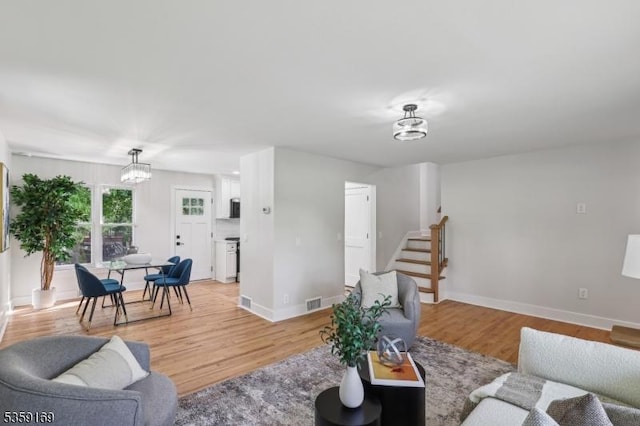 158 Old Indian Rd, West Orange Twp, NJ 07052 - living room featuring a chandelier, stairs, light wood-type flooring, and baseboards