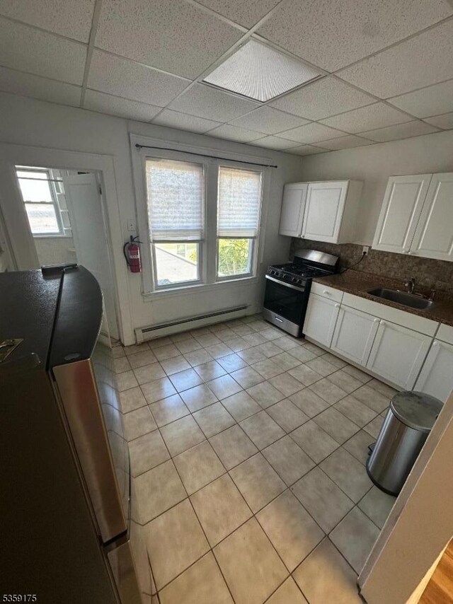 kitchen with stainless steel gas stove, baseboard heating, a sink, a drop ceiling, and plenty of natural light