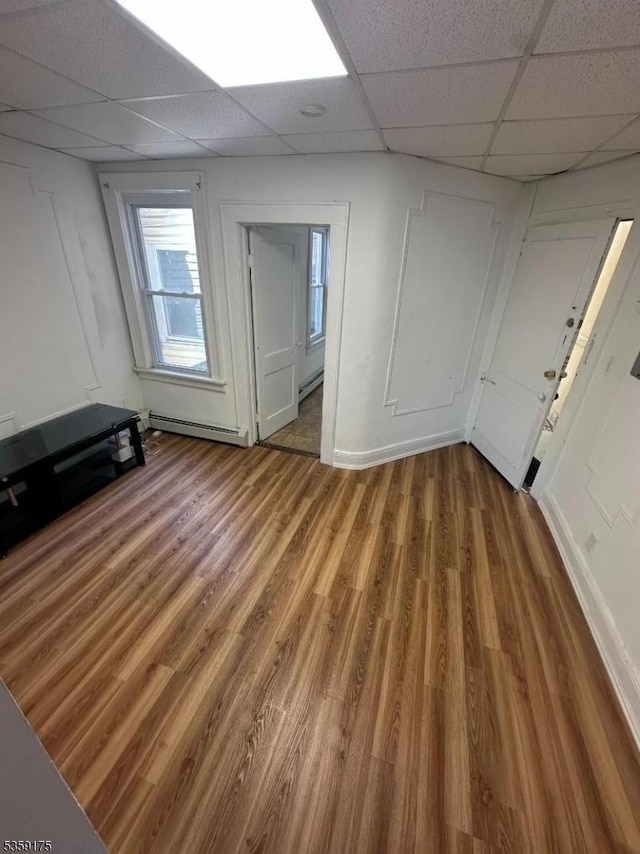 entrance foyer with light wood finished floors, a drop ceiling, and a baseboard radiator