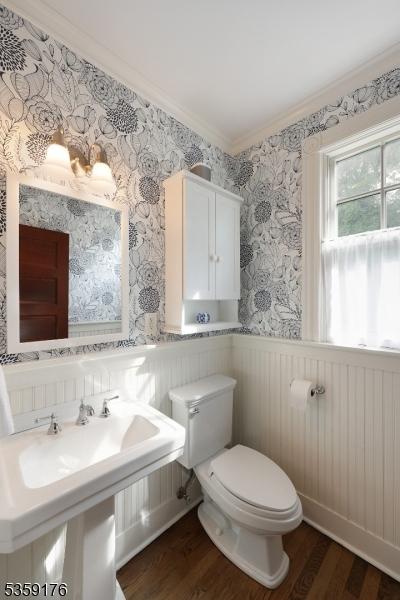 216 Kimball Ave, Westfield Town, NJ 07090 - half bathroom with wood finished floors, toilet, ornamental molding, a wainscoted wall, and a sink