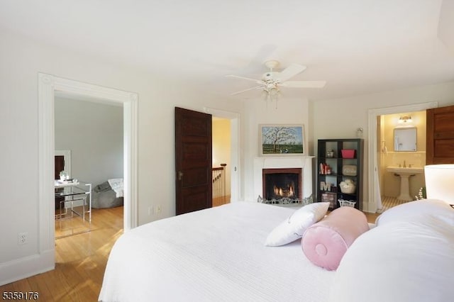 216 Kimball Ave, Westfield Town, NJ 07090 - bedroom with wood finished floors, a lit fireplace, ensuite bathroom, a ceiling fan, and baseboards