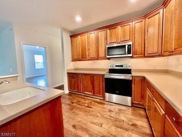 24 Ridgeview Ln Unit 24, Mount Arlington Boro, NJ 07856 - kitchen featuring appliances with stainless steel finishes, a sink, brown cabinetry, light wood-style floors, and light countertops