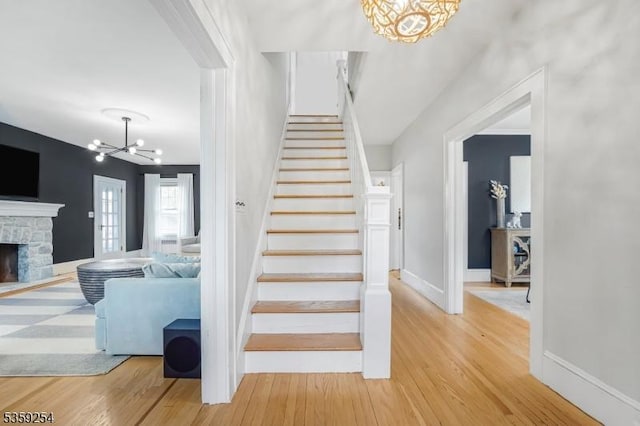 114 Hoagland Ave, Rockaway Boro, NJ 07866 - stairway with a chandelier, wood finished floors, a stone fireplace, and baseboards