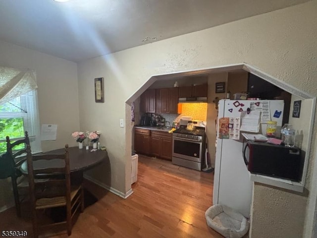 166 Fulton St, New Brunswick City, NJ 08901 - kitchen featuring stainless steel gas stove, light wood-type flooring, black microwave, a textured wall, and freestanding refrigerator