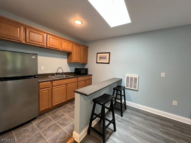 1 Lepont St, Stanhope Boro, NJ 07874 - kitchen featuring freestanding refrigerator, black microwave, a breakfast bar area, dark countertops, and a peninsula