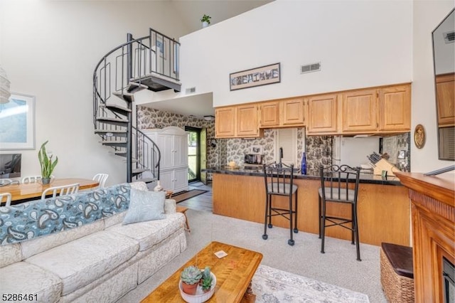 2 Sunrise Dr Unit 6, Vernon Twp, NJ 07462 - kitchen featuring a towering ceiling, a peninsula, dark countertops, a kitchen bar, and light colored carpet