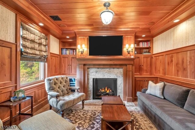 259 Indian Trail Dr, Franklin Lakes Boro, NJ 07417 - living room featuring built in shelves, a warm lit fireplace, wooden ceiling, wood walls, and crown molding
