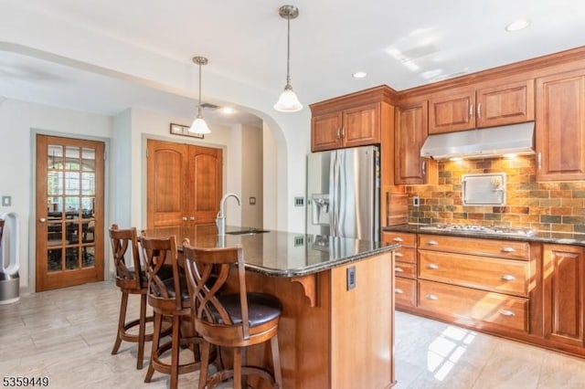 947 Madison Ave, Plainfield City, NJ 07060 - kitchen featuring appliances with stainless steel finishes, under cabinet range hood, a sink, arched walkways, and brown cabinetry