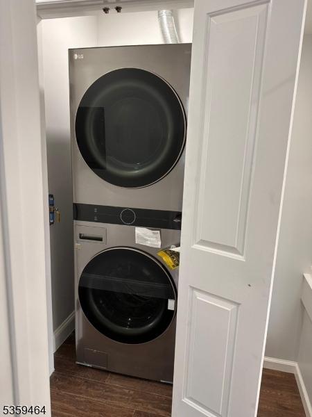 228 78th St, North Bergen Twp, NJ 07047 - laundry area featuring stacked washer / drying machine, dark wood-style floors, and baseboards