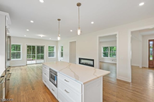 1 Willow Pl, East Hanover Twp, NJ 07936 - kitchen featuring white cabinets, recessed lighting, light wood-type flooring, hanging light fixtures, and a fireplace