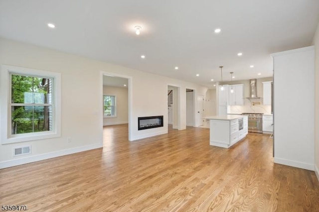 1 Willow Pl, East Hanover Twp, NJ 07936 - unfurnished living room with light wood-style floors, recessed lighting, baseboards, and a glass covered fireplace