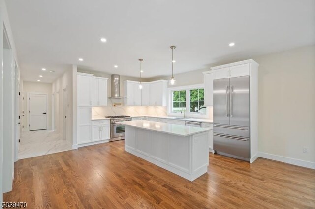 1 Willow Pl, East Hanover Twp, NJ 07936 - kitchen with premium appliances, wall chimney range hood, light countertops, a kitchen island, and white cabinetry