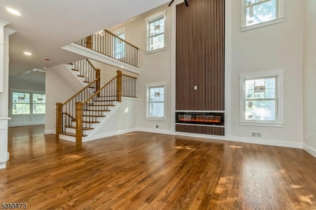 32 N Ave, Fanwood Boro, NJ 07023 - unfurnished living room with a towering ceiling, wood finished floors, stairway, baseboards, and a glass covered fireplace