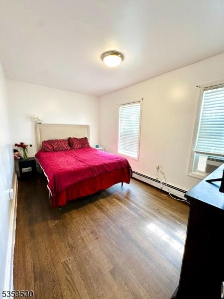 341 S 18th St, Newark City, NJ 07103 - bedroom with a baseboard heating unit, wood finished floors, multiple windows, and cooling unit