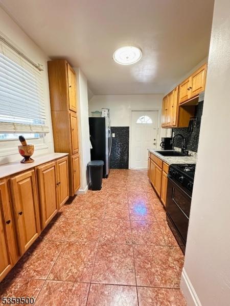 341 S 18th St, Newark City, NJ 07103 - kitchen with black range, freestanding refrigerator, a sink, light countertops, and backsplash