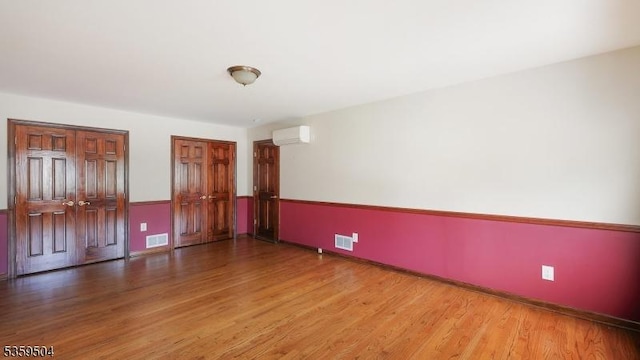 700 Schoolhouse Ln, Bound Brook Boro, NJ 08805 - empty room with an AC wall unit, wood finished floors, and baseboards