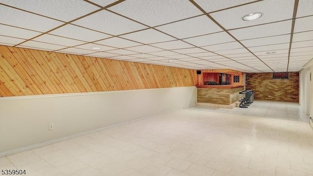 700 Schoolhouse Ln, Bound Brook Boro, NJ 08805 - finished below grade area with a drop ceiling, wooden walls, brick wall, baseboards, and bar