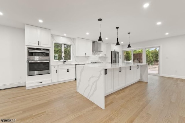 409 Washington St, Carlstadt Boro, NJ 07072 - kitchen with appliances with stainless steel finishes, light wood finished floors, white cabinetry, a sink, and wall chimney exhaust hood