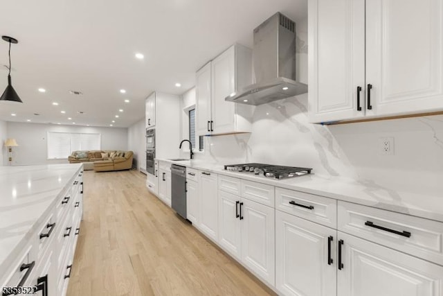 409 Washington St, Carlstadt Boro, NJ 07072 - kitchen with wall chimney range hood, appliances with stainless steel finishes, a sink, light wood-style flooring, and white cabinets