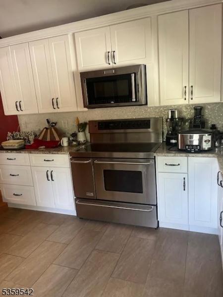2 Erin Ln, Vernon Twp, NJ 07422 - kitchen featuring range with two ovens, white cabinets, tasteful backsplash, and light wood-style floors