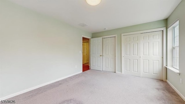 612 Magnolia Rd, North Brunswick Twp, NJ 08902 - unfurnished bedroom featuring two closets, light colored carpet, multiple windows, and baseboards