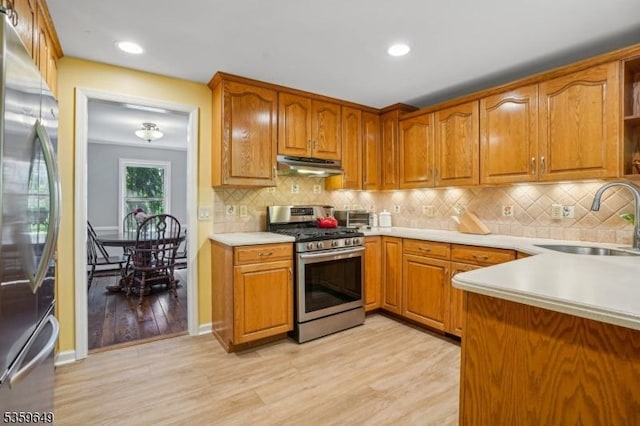 1794 Long Hill Rd, Long Hill Twp, NJ 07946 - kitchen with appliances with stainless steel finishes, under cabinet range hood, a sink, light wood finished floors, and brown cabinets
