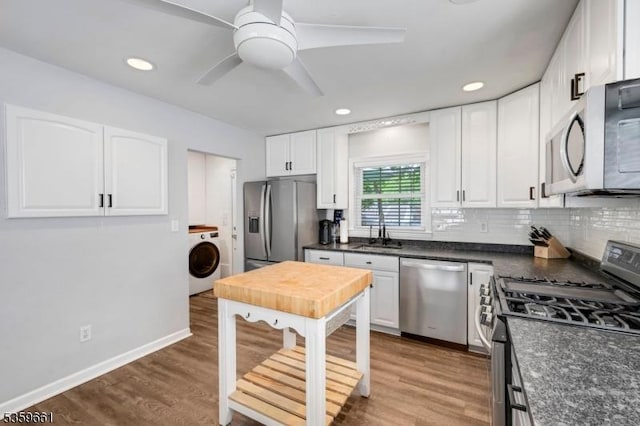 46 Sunrise Ter, Cedar Grove Twp, NJ 07009 - kitchen with stainless steel appliances, washer / dryer, dark countertops, white cabinetry, and wood finished floors