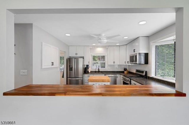 46 Sunrise Ter, Cedar Grove Twp, NJ 07009 - kitchen with appliances with stainless steel finishes, wooden counters, a sink, backsplash, and a peninsula