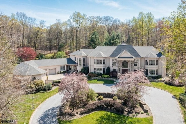 23 Stoningham Dr, Warren Twp, NJ 07059 - view of front of home with curved driveway, an attached garage, a front lawn, and a view of trees