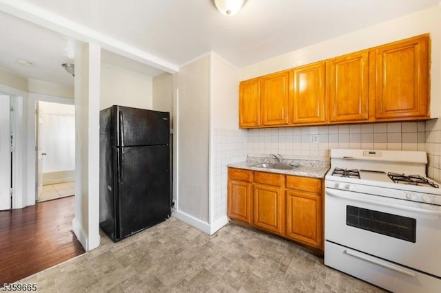 28 Beechwood Pl, Irvington Twp, NJ 07111 - kitchen with freestanding refrigerator, white gas range, a sink, brown cabinets, and light countertops