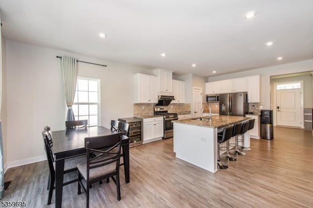 76 Trafalgar Ct, Sparta Twp, NJ 07871 - kitchen featuring stainless steel appliances, a sink, light stone counters, a breakfast bar area, and an island with sink