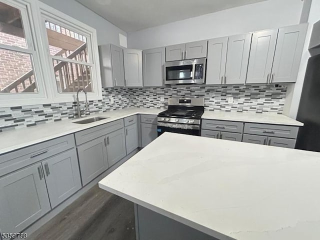 207 Tremont Ave, East Orange City, NJ 07018 - kitchen featuring appliances with stainless steel finishes, gray cabinetry, a sink, dark wood-type flooring, and backsplash