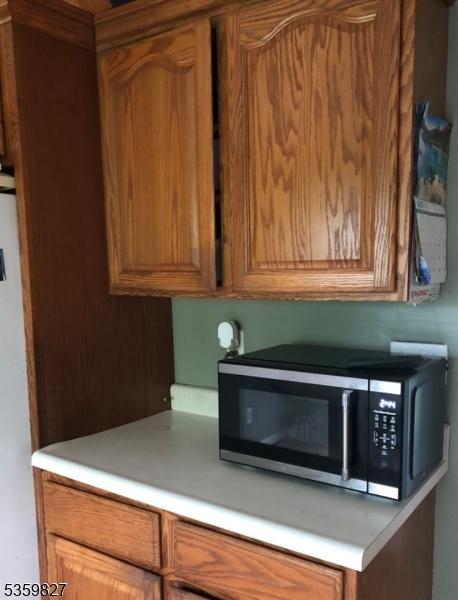 13 Elmwood Dr, Mansfield Twp, NJ 07840 - kitchen with stainless steel microwave, brown cabinetry, light countertops, and freestanding refrigerator