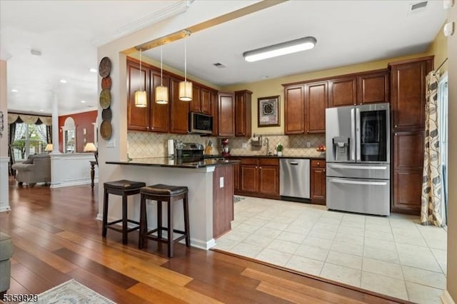 2420 Canterbury Ln, North Brunswick Twp, NJ 08902 - kitchen with appliances with stainless steel finishes, dark countertops, a peninsula, a breakfast bar area, and light wood-type flooring
