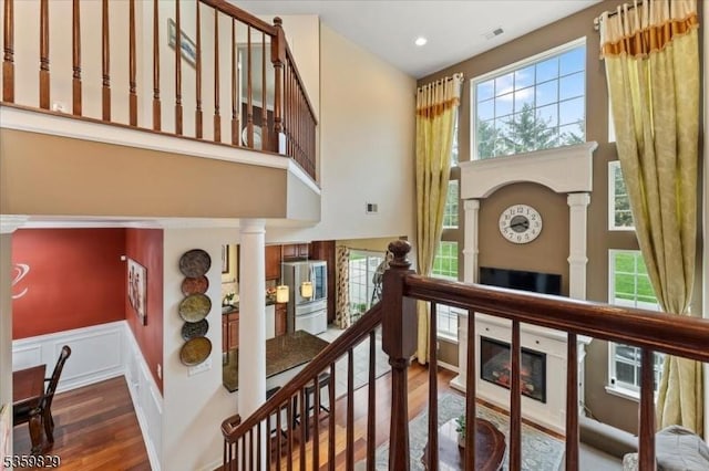 2420 Canterbury Ln, North Brunswick Twp, NJ 08902 - stairway featuring decorative columns, wood finished floors, a towering ceiling, plenty of natural light, and a glass covered fireplace