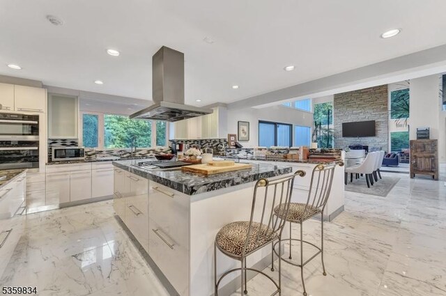 41 Park Way W, Orange Twp, NJ 07052 - kitchen featuring island exhaust hood, stainless steel microwave, a breakfast bar area, healthy amount of natural light, and recessed lighting