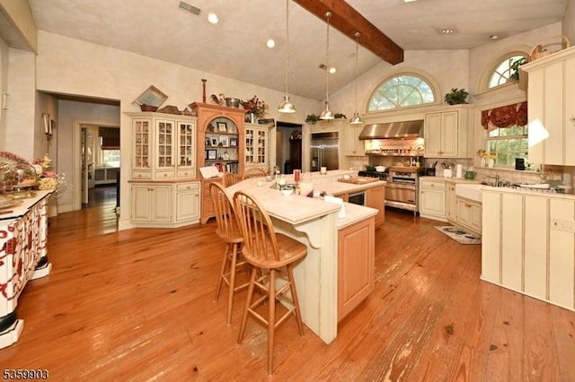 777 E Ridgewood Ave, Ridgewood Village, NJ 07450 - kitchen featuring beam ceiling, a breakfast bar, light countertops, wall chimney range hood, and light wood-style floors