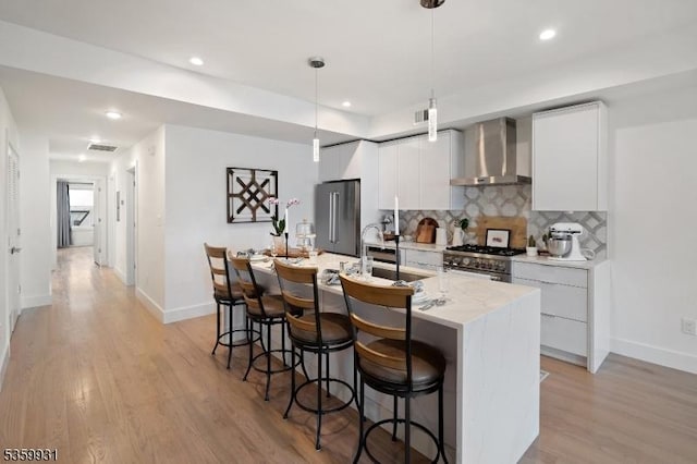 27 Leonard St Unit 2, Jersey City, NJ 07307 - kitchen with wall chimney exhaust hood, high end appliances, a breakfast bar, decorative backsplash, and light wood-type flooring