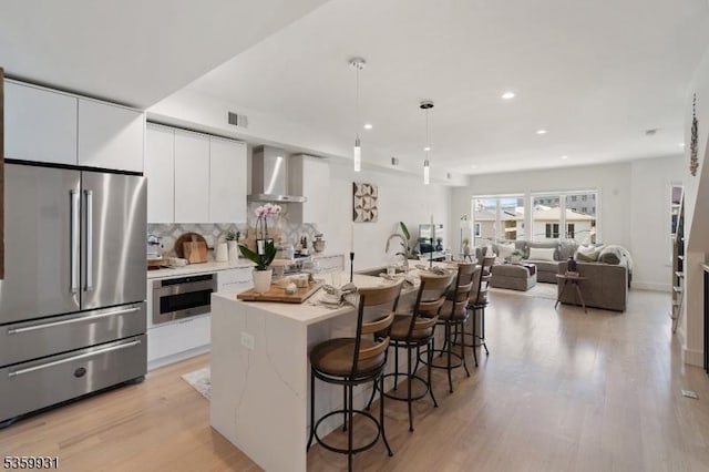 27 Leonard St Unit 2, Jersey City, NJ 07307 - kitchen with appliances with stainless steel finishes, wall chimney exhaust hood, white cabinets, recessed lighting, and a breakfast bar area