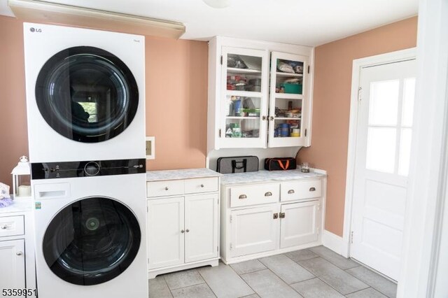 61 Park Ave, Flemington Boro, NJ 08822 - laundry room with stacked washer / drying machine, cabinet space, and light tile patterned flooring