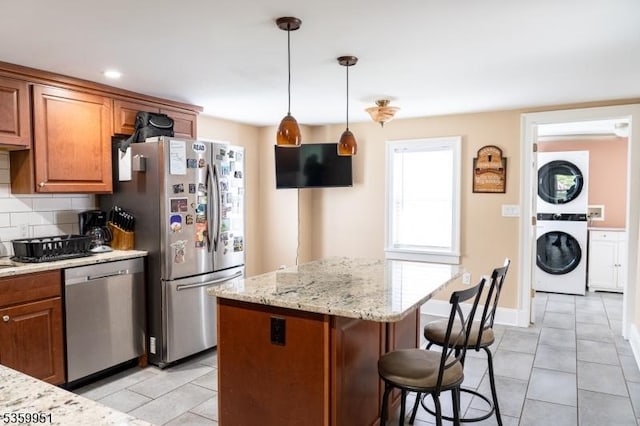 61 Park Ave, Flemington Boro, NJ 08822 - kitchen featuring stacked washer and clothes dryer, appliances with stainless steel finishes, light tile patterned flooring, a breakfast bar, and brown cabinets