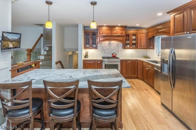 18 W Circuit Dr, Roxbury Twp, NJ 07876 - kitchen featuring stainless steel appliances, light wood finished floors, brown cabinetry, hanging light fixtures, and a sink